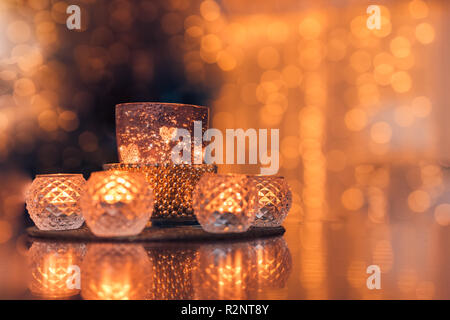 Cozy home interior decor, burning candles in glasses with blurred romantic lights background. Christmas or winter season autumn home interior Stock Photo