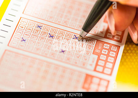 Close-up Of Person's Hand Marking Number On Lottery Ticket With Pen Stock Photo