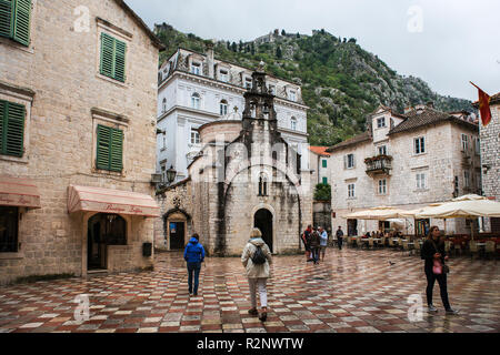 St. Luke's Church (Crkva Sv Luke) in the eponymous square (Trg Sv Luke) and the city fortifications above on a rainy afternoon: Kotor, Montenegro Stock Photo