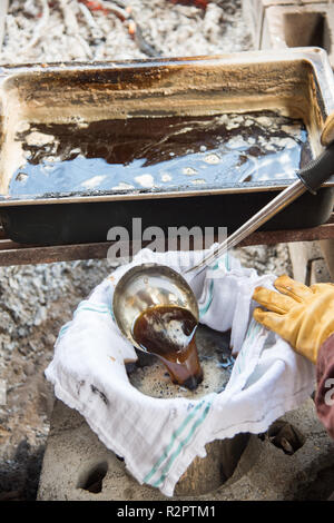 Detail of maple sap boil to make homemade syrup with pan, bucket, cloth and person ladling liquid in outdoor setting in Minnesota. Stock Photo