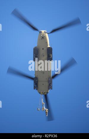 Army paratroopers assigned to the 4th Infantry Brigade Combat Team (Airborne), 25th Infantry Division, U.S. Army Alaska, jump from a CH-47 Chinook helicopter during airborne training at Joint Base Elmendorf-Richardson, Alaska, Nov. 1, 2018. The Soldiers of 4/25 belong to the only American airborne brigade in the Pacific and are trained to execute airborne maneuvers in extreme cold weather and high altitude environments in support of combat, partnership and disaster relief operations. Army aviators from B Company, 1st Battalion, 52nd Aviation Regiment out of Fort Wainwright, operated CH-47 Chin Stock Photo