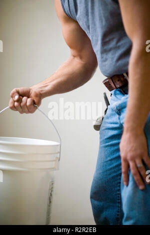 Male builder carrying a white bucket. Stock Photo