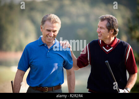 Two mature men enjoying a game together on a golf course. Stock Photo