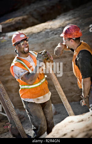 Two builders on a construction site talking and laughing Stock Photo