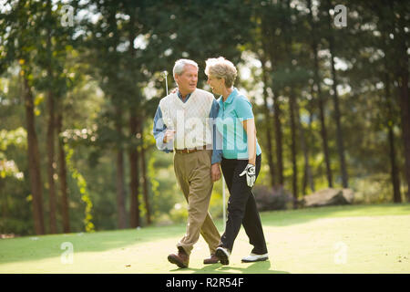 Older couple walking on golf course Stock Photo
