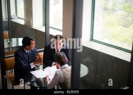 Three business colleagues sitting doing work in an office building. Stock Photo