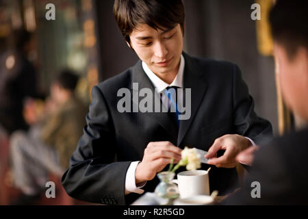 Young businessman sitting at an outdoor cafe table with a colleague. Stock Photo