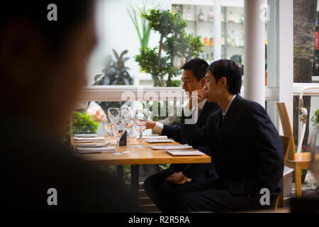 Two young adult businessmen sitting in a restaurant. Stock Photo