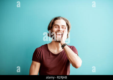 Emotional portrait of a young caucasian bearded man with long hair dressed in t-shirt on the colorful background Stock Photo