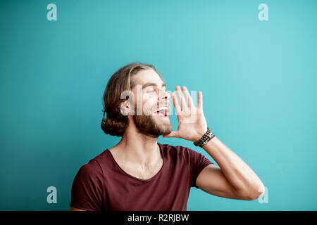 Emotional portrait of a young caucasian bearded man with long hair dressed in t-shirt on the colorful background Stock Photo