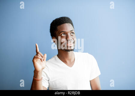 Portrait of a young african man dressed in white t-shirt having an idea on the colorful background Stock Photo