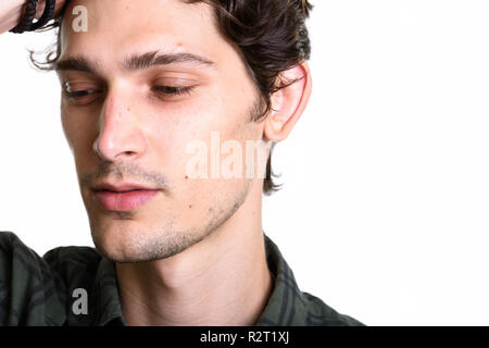 Close up of young handsome man brushing hair back while thinking Stock Photo