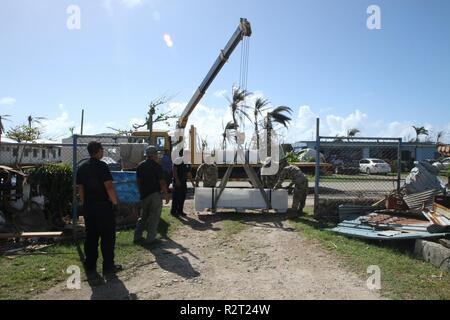 U.S. Army Reserve Soldiers with the 797th Engineer Company (Vertical), 9th Mission Support Command, and personnel with the Department of Fire and Emergency Services offload a FEMA tent as part of the Temporary Emergency Tent and Roofing Installation Support program implemented by the Commonwealth of the Northern Mariana Islands government and the FEMA, at a residency in Koblerville, Saipan, CNMI, Nov. 9, 2018. Service members from Joint Region Marianas and other units from within U.S. Indo-Pacific Command assigned to Task Force-West are providing Department of Defense support to the CNMI’s civ Stock Photo