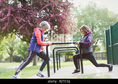 Active senior female runners stretching legs in park Stock Photo