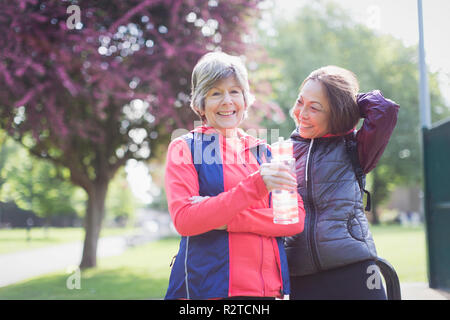 Portrait confident active senior female runner friends drinking water in park Stock Photo