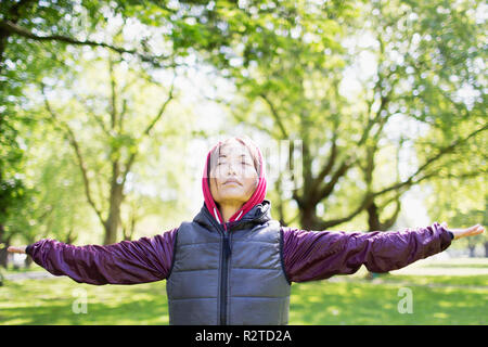 Portrait serene active senior woman stretching in park Stock Photo