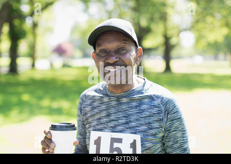 Portrait smiling, confident active senior man drinking coffee before sports race in park Stock Photo