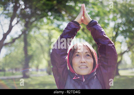 Active senior woman exercising, practicing yoga in park Stock Photo
