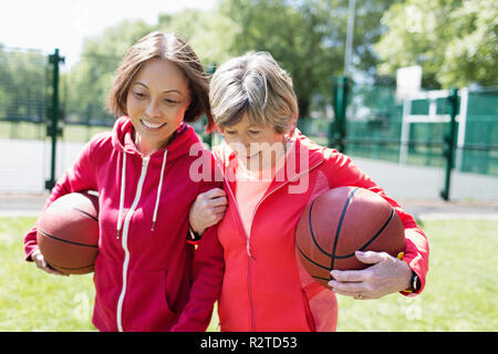 Active senior women friends playing basketball in sunny park Stock Photo