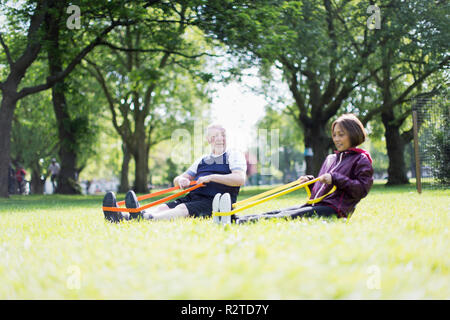 Active senior couple exercising, using resistance bands in park Stock Photo