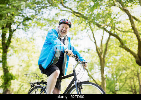 Portrait smiling active senior man riding bike in park Stock Photo