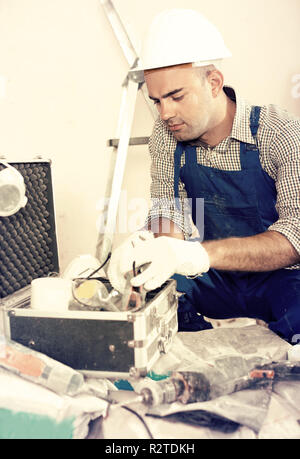 Portrait of worker builder searching tools for repair in toolbox Stock Photo