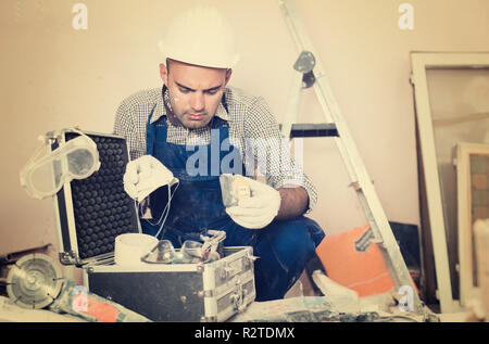 worker builder is carefully looking  tools for repair in toolbox Stock Photo