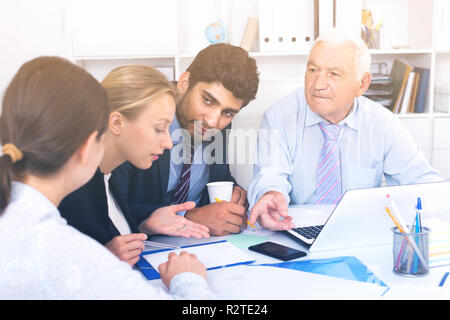 Managers are writing financial reports and discussing with mature boss in the office. Stock Photo