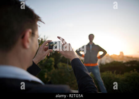 Young man taking a photograph of his friend on a digital camera. Stock Photo
