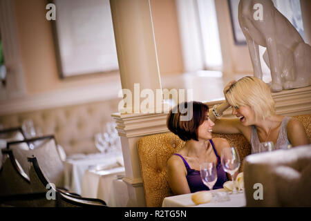 Two mid-adult woman sitting talking at a restaurant. Stock Photo