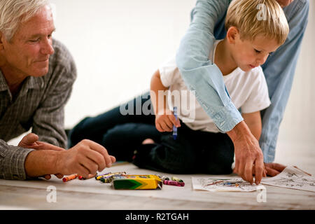 Toddler drawing and playing with his grandparents. Stock Photo