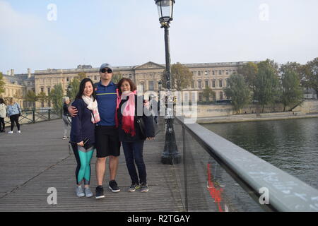 Peoples on Pont des Arts footbridge on the Seine River and People walking across a pedestrian bridge over the River Seine facing the Louvre museum Stock Photo