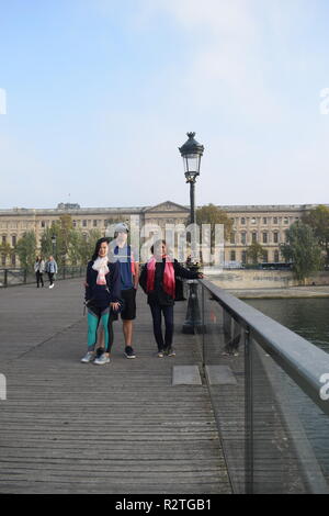 Peoples on Pont des Arts footbridge on the Seine River and People walking across a pedestrian bridge over the River Seine facing the Louvre museum Stock Photo