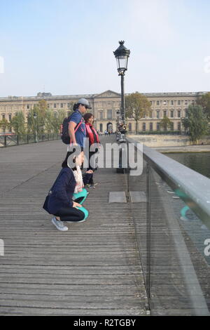 Peoples on Pont des Arts footbridge on the Seine River and People walking across a pedestrian bridge over the River Seine facing the Louvre museum Stock Photo