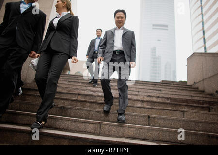 Group of businesspeople walking down a flight of stairs in the city. Stock Photo