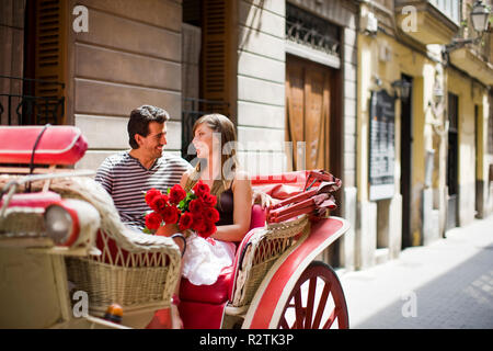 Young adult couple sitting in a horse-drawn cart. Stock Photo