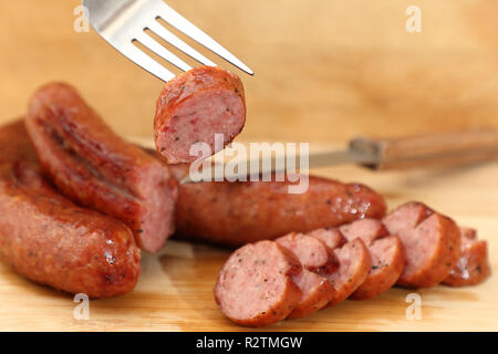 Smoked juicy sausage on a fork Stock Photo