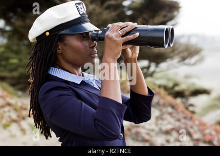 Woman wearing navy hat looking through binoculars Stock Photo