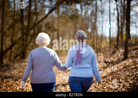 Two elderly woman holding hands walking in the forest. Stock Photo