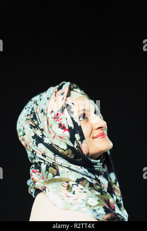 Portrait smiling, confident woman in floral hijab looking up Stock Photo
