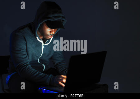 Teenage boy in hoody leaning over laptop Stock Photo