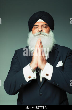Portrait serene senior man in turban praying with eyes closed Stock Photo