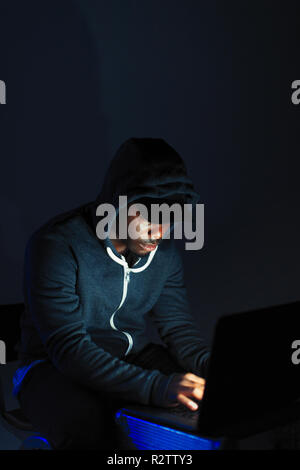 Teenage boy in hoody sitting at laptop Stock Photo