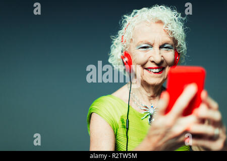 Carefree senior woman with headphones and mp3 player listening to music Stock Photo