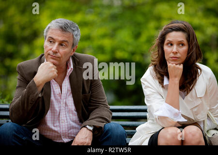 Unhappy couple sit next to each other on a park bench. Stock Photo
