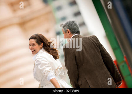 Middle aged woman looks over her shoulder and smiles at the camera while walking with her husband. Stock Photo