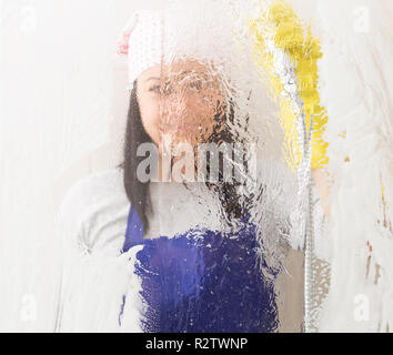 Unclear image of woman wearing grey blouse and blue apron rinsing shower glass Stock Photo