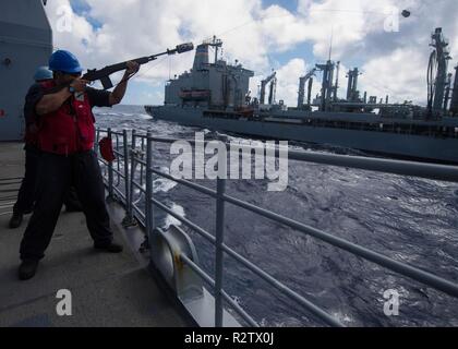 PACIFIC OCEAN (Nov. 06, 2018) Gunner's Mate 3rd Class Daniel Zhang, from Houston fires a shot line to the fleet replenishment oiler USNS Guadalupe (T-AO 200) during a replenishment-at-sea (RAS) aboard the Ticonderoga-class guided-missile cruiser USS Mobile Bay (CG 53). Mobile Bay is underway conducting routine operations as part of Carrier Strike Group (CSG) 3 in the U.S. Pacific Fleet area of operations. Stock Photo