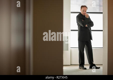Businessman in suit stands outdoors with arms folded. Stock Photo