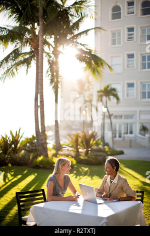 Two business colleagues sitting at outside table on lawn, for meeting. Stock Photo